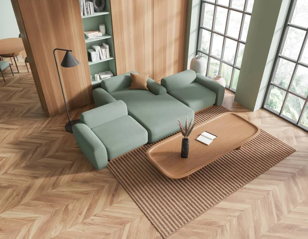 Top view of stylish living room with green walls, dark wooden floor, comfortable green couch standing near long wooden coffee table and dark wooden bookcase. 3d rendering
