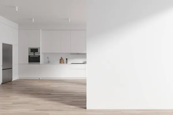 Interior of modern kitchen with white walls, wooden floor, big fridge and comfortable white cupboards and cabinets with built in cooker, sink and oven. Copy space wall on the right. 3d rendering