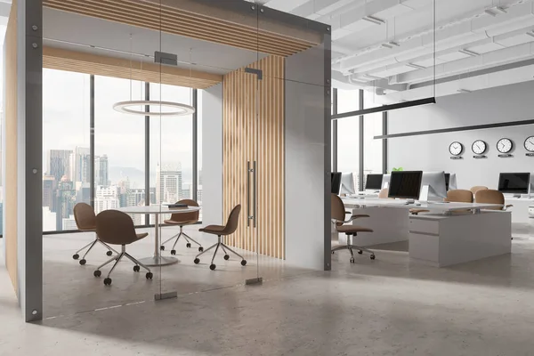 Corner of modern open space office with gray and wooden walls, concrete floor, computer desks with beige chairs, clocks showing world time and cozy conference room with round table. 3d rendering