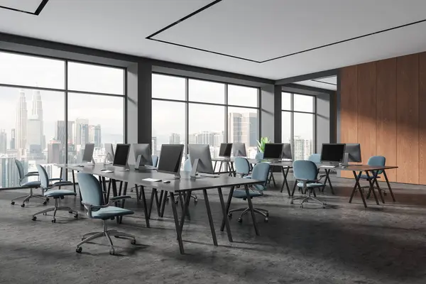 Modern office loft interior with pc computers, side view coworking corner with armchairs and desk on grey concrete floor. Workspace and panoramic window on Kuala Lumpur. 3D rendering