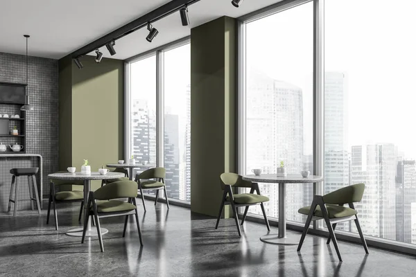 Corner of stylish restaurant with green and gray tiled walls, concrete floor, gray bar counter with stools and round tables with green chairs standing near windows with cityscape. 3d rendering