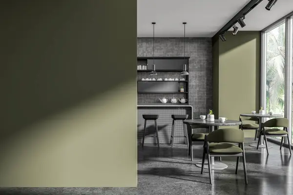 Interior of stylish restaurant with green and gray tiled walls, concrete floor, comfortable gray bar counter with stools, round tables with green chairs and mock up wall on the left. 3d rendering