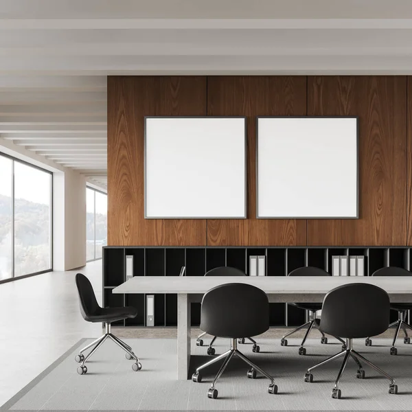 Interior of modern office meeting room with white and wooden walls, long white conference table with chairs, bookshelves with folders and two square mock up posters hanging above them. 3d rendering