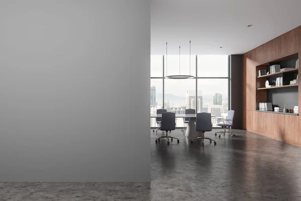 Interior of stylish meeting room with gray walls, concrete floor, long conference table with gray chairs, dark wooden bookcase and copy space wall on the left. 3d rendering