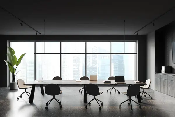Dark office interior with chairs and laptop on desk, grey granite floor. Modern meeting and coworking space, sideboard with tv and decoration. Panoramic window on Singapore. 3D rendering