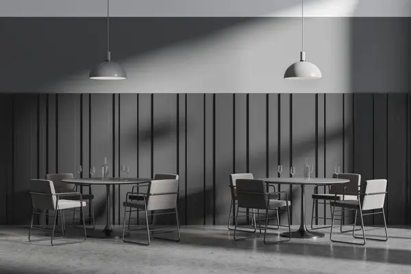 Dark restaurant interior with armchairs and round table in row, glasses and bottle. Stylish cafe eating space with lamps, paneling and grey concrete floor. 3D rendering