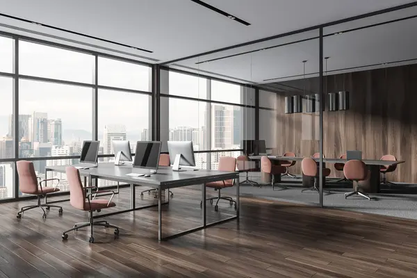 Dark wooden office interior with pc computers on shared table and armchairs. Corner view of glass conference zone with table and panoramic window on Kuala Lumpur. 3D rendering