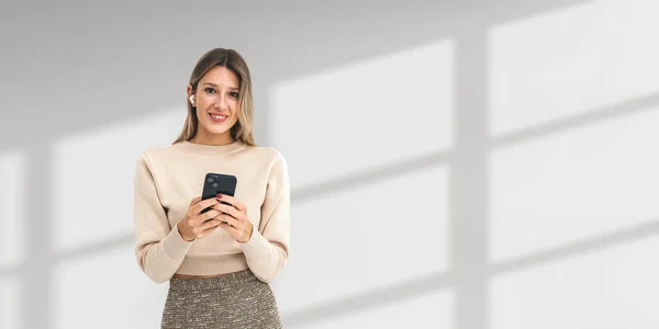 Портрет Веселой Молодой Европейской Предпринимательницы Использующей Смартфон Наушники Стоящие Белом — стоковое фото