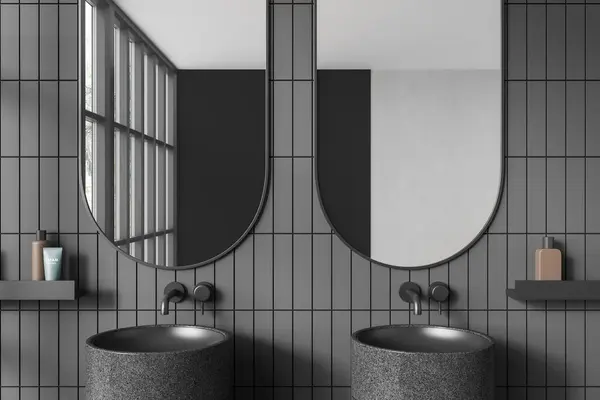 ダークタイルのホテルのバスルームのインテリアにはダブルシンクとアクセサリー付きの棚があります 灰色の壁に2つの洗面台と楕円形の鏡 反射するパノラマウィンドウ 3Dレンダリング — ストック写真