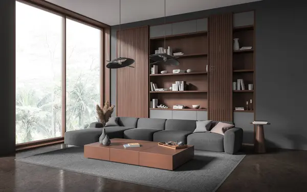 Corner of stylish living room with gray and wooden walls, concrete floor, cozy gray couch standing near long coffee table and dark wooden bookcase behind it. 3d rendering