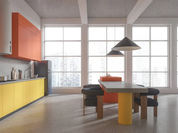 Bright home kitchen interior with eating table and armchairs, grey granite floor. Orange and yellow cabinet with refrigerator and kitchenware, panoramic window on skyscrapers. 3D rendering