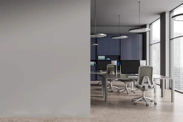 Interior of stylish open space office with gray walls, stone floor, row of computer tables with gray chairs and blue bookcase with folders. Copy space wall on the left. 3d rendering