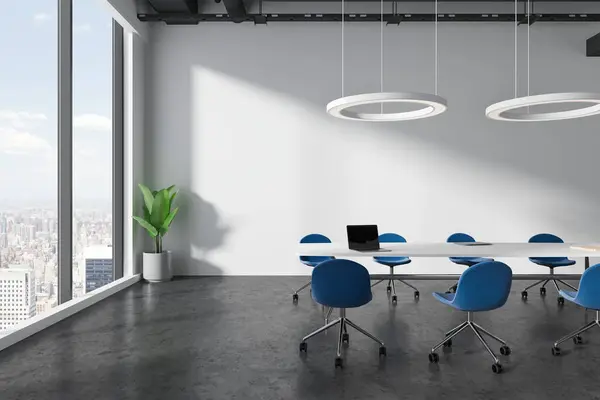 White office interior with blue chairs and table with laptop, grey concrete floor. Modern workspace with panoramic window on New York skyscrapers. 3D rendering
