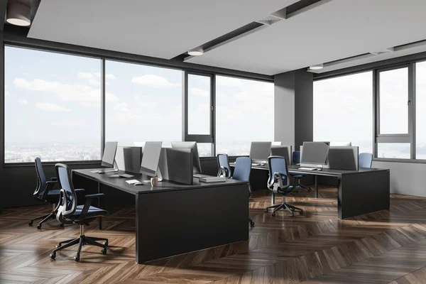 Corner of stylish open space office with gray walls, wooden floor, row of gray computer desks with blue chairs and big windows with cityscape. 3d rendering