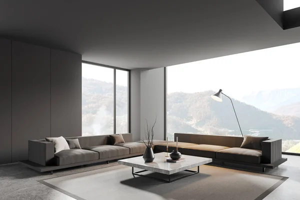 Corner of stylish living room with gray walls, concrete floor, two comfortable gray couches standing on carpet near big windows and gray square coffee table. 3d rendering