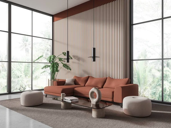 Corner of modern living room with brown and wooden walls, concrete floor, cozy brown couch and two white poufs standing on carpet near glass coffee table. 3d rendering