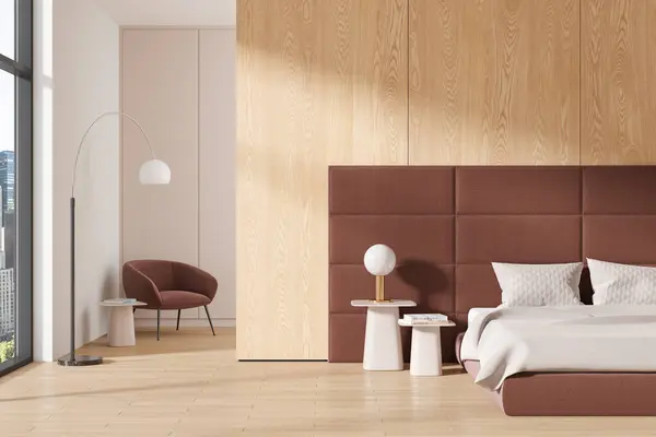Stylish home bedroom interior bed with accent wall and nightstand, armchair with lamp behind partition and hardwood floor. Panoramic window on skyscrapers. 3D rendering