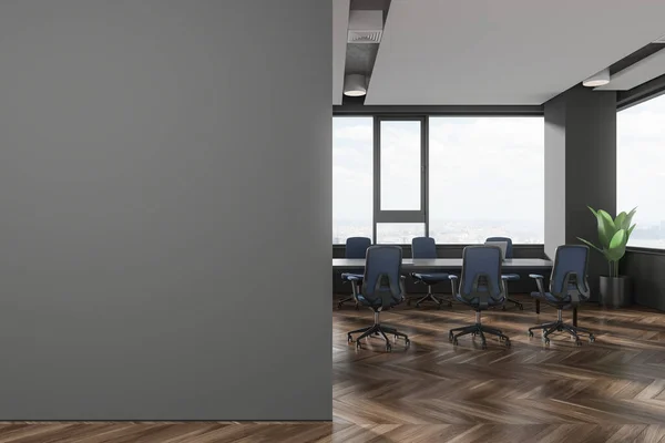 Interior of stylish office meeting room with gray walls, wooden floor, long conference table with blue chairs standing near big window and copy space wall on the left. 3d rendering