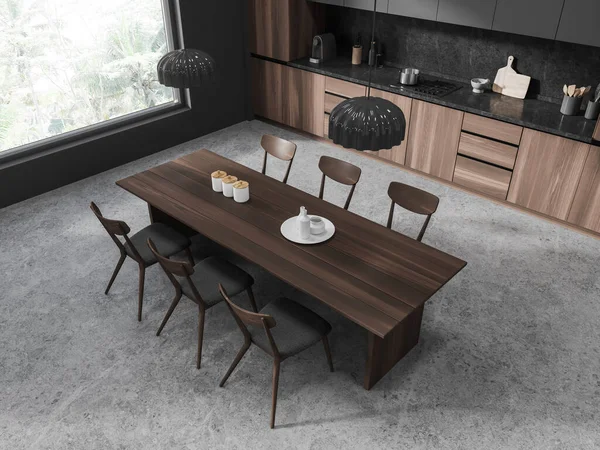 Top view of dark home kitchen interior with dining table and chairs, grey concrete floor. Cooking corner with cabinet and panoramic window on tropics. 3D rendering