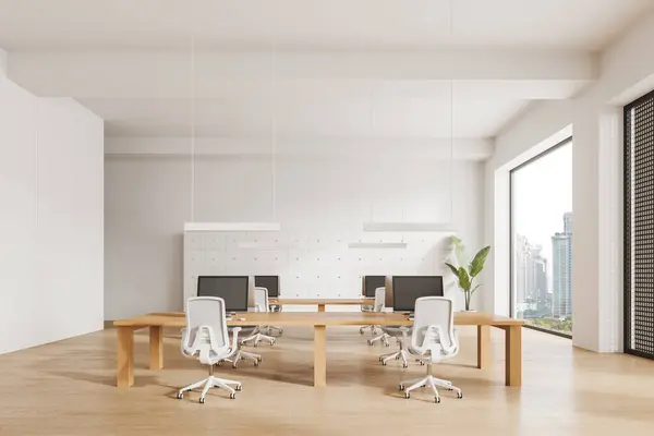 White office interior with pc computers on shared desk, armchairs in row on hardwood floor. Minimalist workspace with panoramic window on skyscrapers. 3D rendering