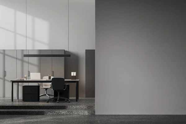 Dark ceo interior with laptop computer on desk and chairs, podium stars on grey granite floor. Modern office space with shelf, mockup copy space empty wall partition. 3D rendering