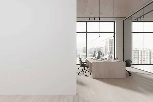 Interior of modern open space office with white walls, wooden floor, rows of massive computer desks with chairs and windows with cityscape. Copy space wall on the left. 3d rendering