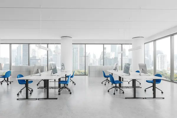 White coworking interior with chairs and pc computers in row, light concrete floor. Stylish office loft with panoramic window on New York skyscrapers. 3D rendering