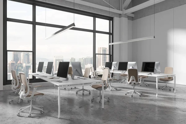 Stylish office interior with pc computers and shared desk in row, side view grey concrete floor. Stylish coworking corner with panoramic window on Kuala Lumpur skyscrapers. 3D rendering