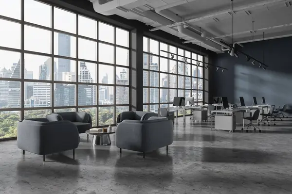 Dark office interior with coworking and lounge corner, side view pc computers on desk in row on grey concrete floor. Panoramic window on Bangkok skyscrapers. 3D rendering