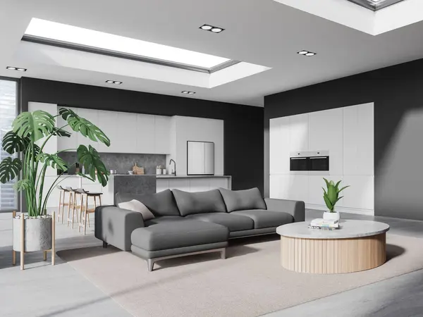 Corner of stylish living room with gray walls, concrete floor, cozy gray sofa standing near round coffee table and comfortable kitchen with island, fridge and white cabinets. 3d rendering