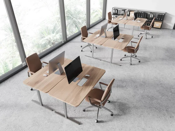 Top view of coworking interior with pc computers on desk, brown armchairs on light concrete floor. Modern office workplace with minimalist furniture and panoramic window. 3D rendering