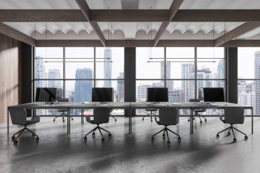 Koltukları ve monitörleri olan karanlık ofis içi gri beton zemin üzerinde sıra sıra dizilmiş masa. Minimalist çalışma alanı ve Bangkok gökdelenlerinin panoramik penceresi. 3B görüntüleme