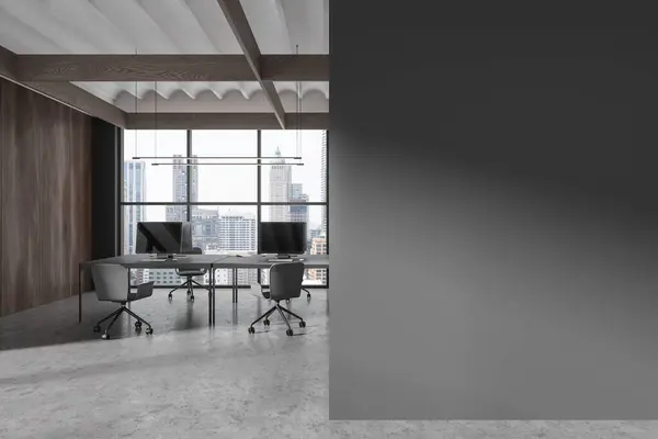 Dark office interior with pc desktop and chairs, table in row on grey concrete floor. Coworking space and panoramic window on Bangkok. Mockup copy space blank partition. 3D rendering