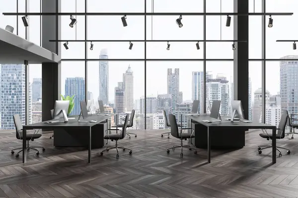 Dark office interior with pc computers and shared desk with armchairs, hardwood floor. Two-storey coworking loft with panoramic window on Bagkok skyscrapers. 3D rendering