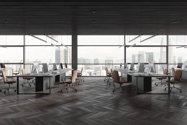 Dark office interior with seats and pc desktop, shared table on hardwood floor. Office business workplace and panoramic window on Kuala Lumpur skyscrapers. 3D rendering