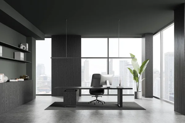 Dark ceo interior with pc computer on desk, armchair on carpet, grey concrete floor. Modern consulting workspace with sideboard and panoramic window on Bangkok skyscrapers. 3D rendering