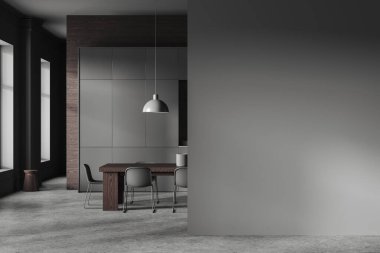 Dark home kitchen interior with dining table, cooking cabinet on grey concrete floor. Eating zone in contemporary apartment with panoramic window. Mockup empty wall partition. 3D rendering