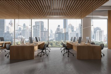 Modern coworking interior with seats and pc desktop, shared table on grey concrete floor. Office business workspace and panoramic window on Bangkok skyscrapers. 3D rendering