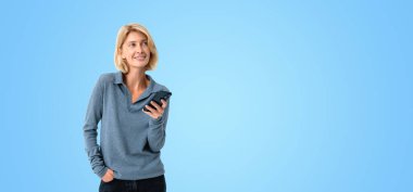 Happy smiling woman portrait using smartphone, empty copy space blue background. Concept of online network, internet communication and digital network