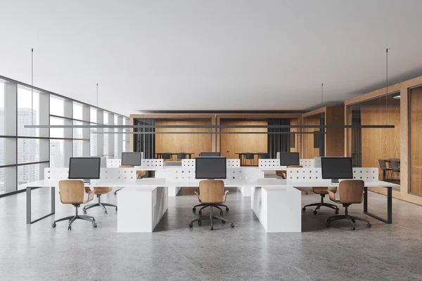 White and wooden office interior with coworking space, pc computers on shared tables with divider. Small glass meeting boxes with curtains in row, panoramic window on skyscrapers. 3D rendering