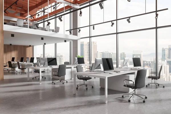Stylish office interior with pc computers and shared desk in row, side view concrete floor. Two-storey stylish coworking space with panoramic window on Kuala Lumpur skyscrapers. 3D rendering