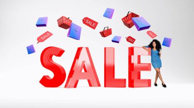 Gülümseyen, uzun boylu, baş parmakları havada, camın yanında duran büyük kırmızı satış mektupları, etiketli alışveriş sepetleri. İyi teklif kavramı ve tavsiye