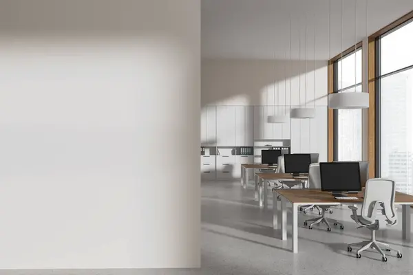 Interior of modern open space office with white walls, concrete floor, row of computer desks and copy space wall on the left. 3d rendering