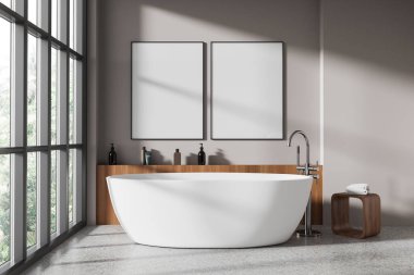 Modern banyo, bej duvarlar, beton zemin ve pencerenin yanında duran rahat beyaz küvet. İki tane poster çerçevesi. 3d oluşturma