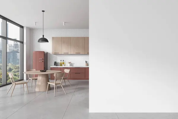 Interior of modern kitchen with white walls, concrete floor, pink cabinets with built in sink and round dining table with chairs. Copy space wall on the right. 3d rendering