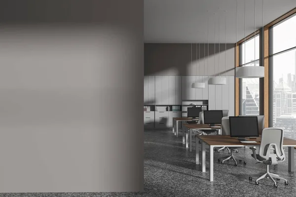 Interior of stylish open space office with gray walls, concrete floor, row of computer desks and copy space wall on the left. 3d rendering