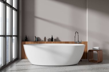 Modern banyo, bej duvarlar, beton zemin ve pencerenin yanında duran rahat beyaz küvet. 3d oluşturma