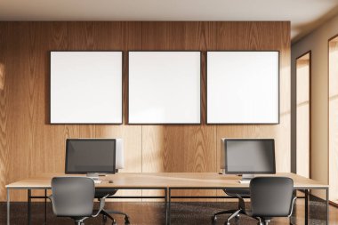 Sandalyelerle ahşap iç mekan, bilgisayar monitörlü masa. Panoramik pencereli rahat çalışma alanı. Sıraya dizilmiş üç tane tuval posteri. 3B görüntüleme