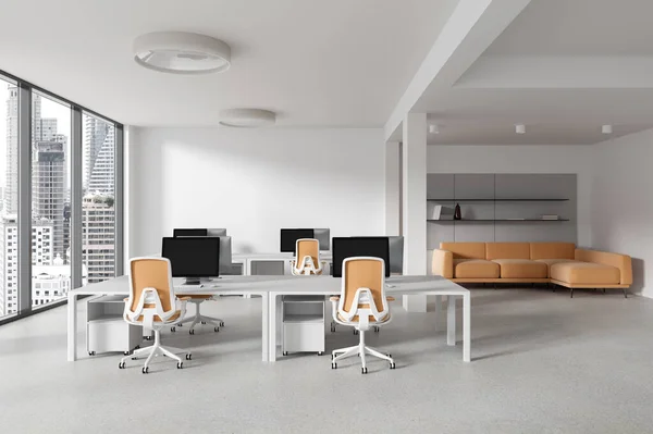 Interior of stylish open space office with white walls, concrete floor and long computer tables with orange chairs. Orange sofa in background. 3d rendering