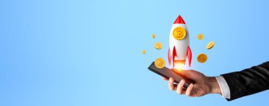 Akıllı telefonlu bir iş adamı, roket havalanıyor ve bitcoin düşüyor. Boş arkaplanı kopyala. Kripto para birimi, iş büyümesi ve çevrimiçi ticaret kavramı